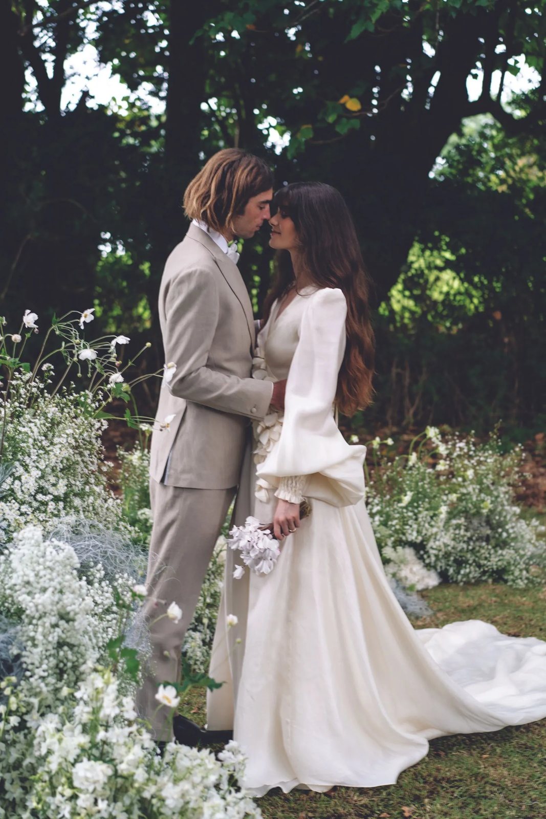 A couple touching foreheads among white flowers in the garden