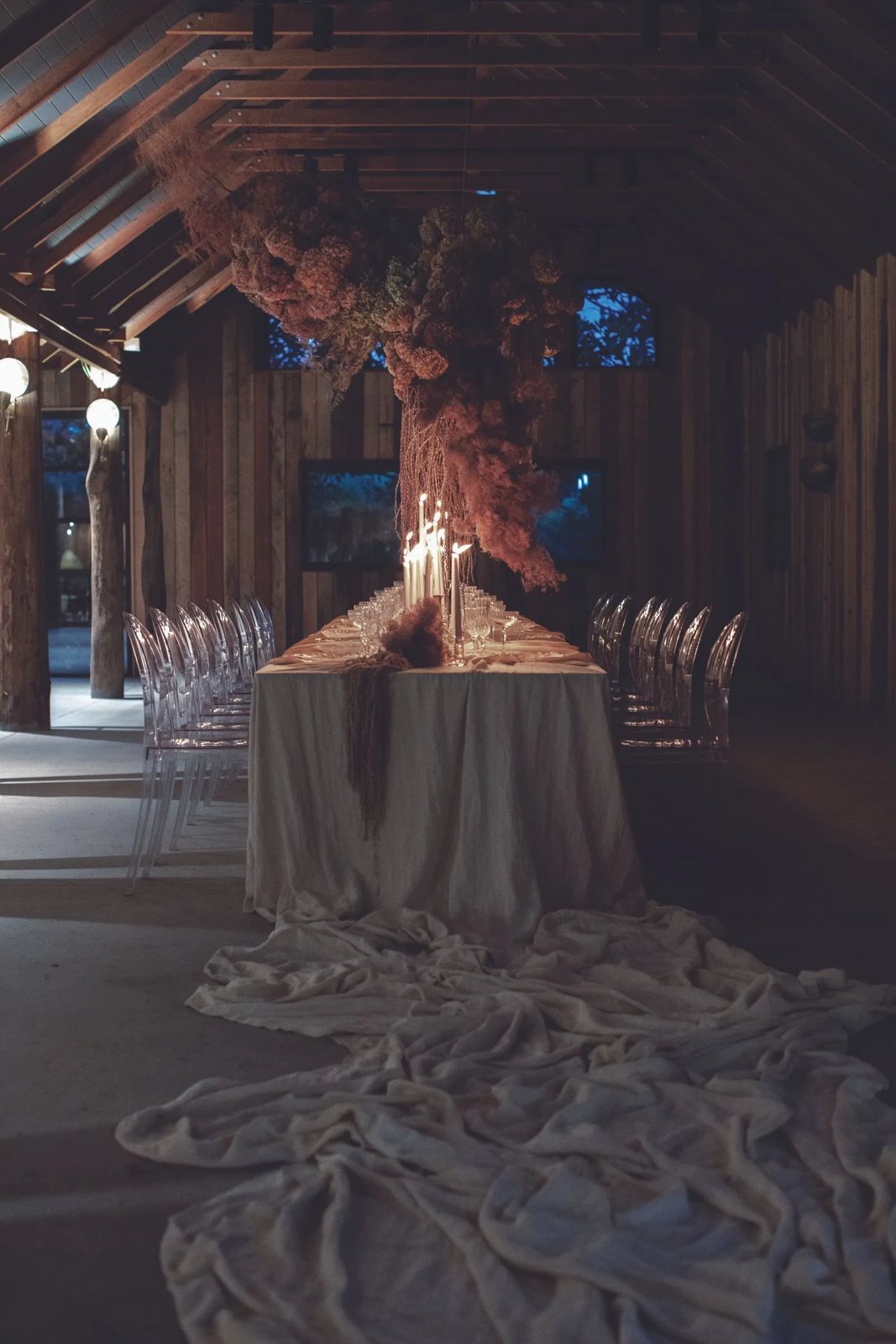 A long table lit by candles inside The Gables, under the timber roof