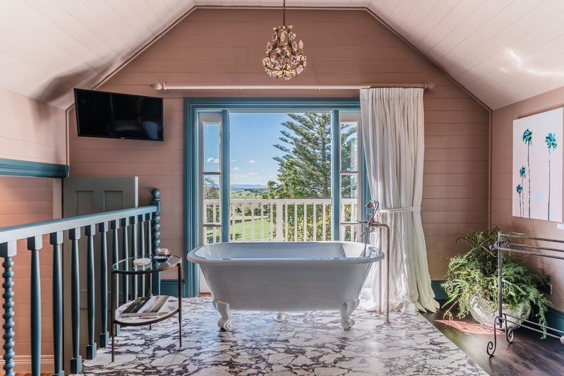 The clawfoot bath in The Loft, French doors open to the garden