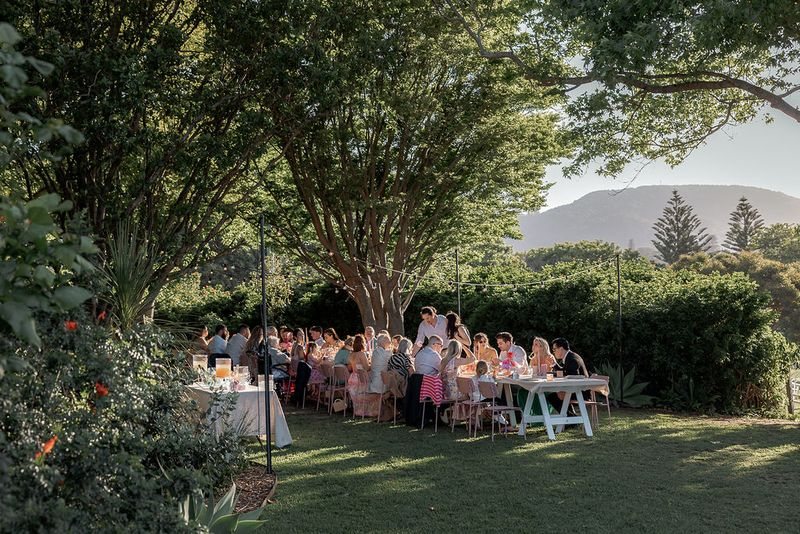 A long-table dinner under the trees, with guests seated on the lawn